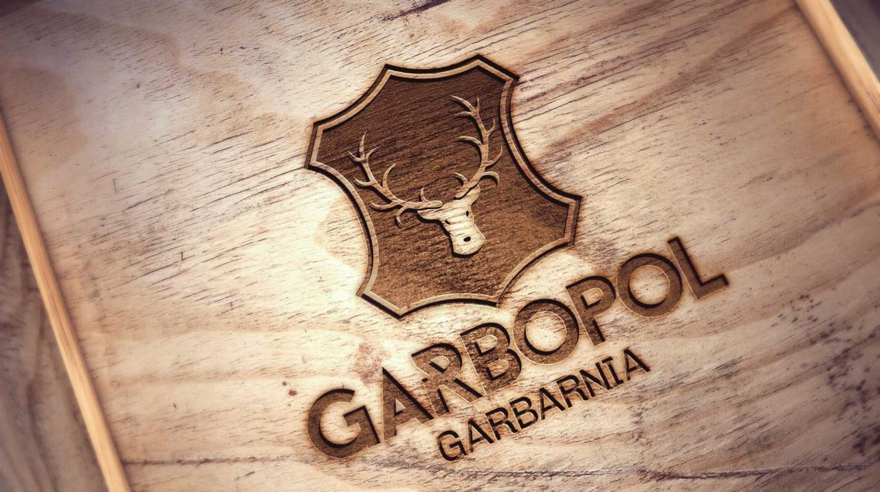 Logo firmy Garbopol Garbarnia, z wizerunkiem głowy jelenia w tarczy, wypalone laserowo na jasnym drewnie.