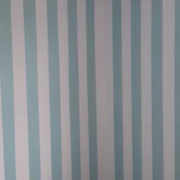 Pokój po świeżym malowaniu w biało-błękitne pionowe pasy, widoczne narzędzia i resztki farby na podłodze.