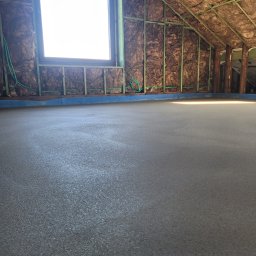 JANKO POSADZKI Janusz Dąbrowski - Świeżo wylana, gładka posadzka jastrychowa w poddaszu z oknem, izolacją z wełny mineralnej i elementami konstrukcji drewnianej.