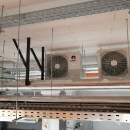 klimatyzacjewarszawa.pl - Dwa agregaty klimatyzacyjne marki Gree zamontowane pod sufitem w pomieszczeniu technicznym, widoczne rury i metalowe konstrukcje podtrzymujące instalacje.