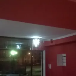 Czerwone ściany w pokoju po remoncie, widoczne lampy sufitowe i okno. Wykończenie wnętrz z dbałością o detale, widoczne listwy przysufitowe.