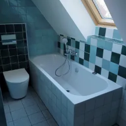 Biała wanna w łazience na poddaszu z oknem dachowym i niebiesko-zielonymi płytkami na ścianach i podłodze, obok toaleta.