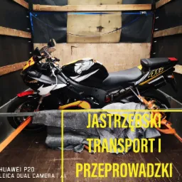 Czarno-żółty motocykl sportowy zabezpieczony pasami transportowymi wewnątrz drewnianej furgonetki, przygotowany do transportu.