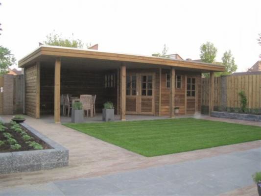 Drewniana altana z płaskim dachem i przeszkleniami, otoczona trawnikiem i rabatą kwiatową, tworząca zaciszną strefę relaksu w ogrodzie.