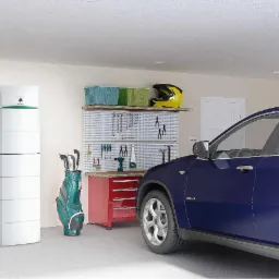 Biała, segmentowa jednostka z zielonym akcentem, prawdopodobnie zasobnik ciepłej wody użytkowej lub bufor ciepła, w garażu obok torby golfowej i narzędzi, z niebieskim SUV-em w tle.