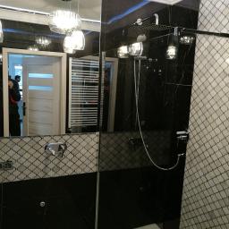 Firma Karczmarski Art - Nowoczesna łazienka z kabiną prysznicową typu walk-in, czarnymi marmurowymi płytkami i mozaiką w marokański wzór, oświetlona wiszącymi lampami z przezroczystego szkła.