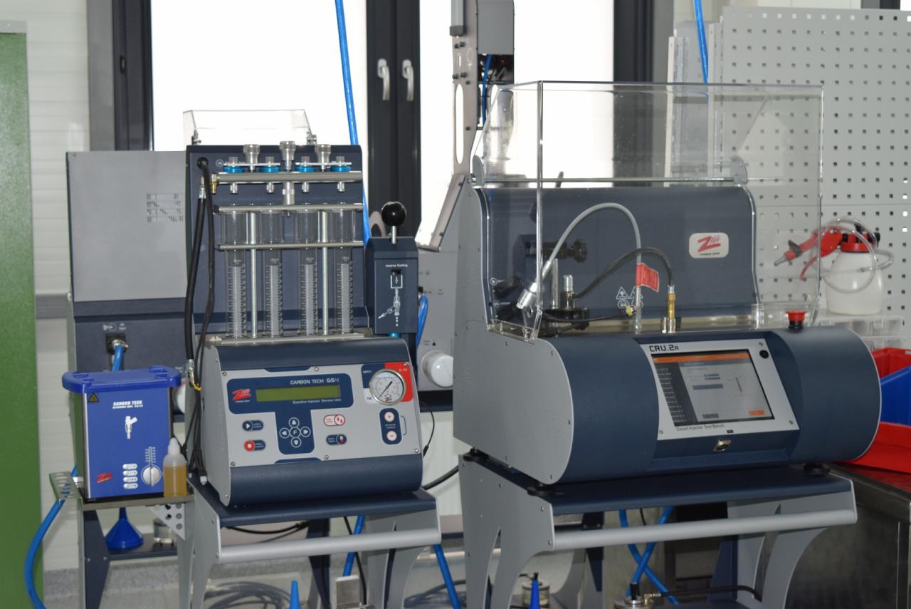 Dwa stanowiska diagnostyczne do testowania wtryskiwaczy paliwa, Carbon Tech SS-II i CRU.2R, ustawione w warsztacie z widocznymi narzędziami i wyposażeniem.