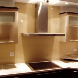 Fragment nowoczesnej kuchni z beżowymi płytkami ściennymi, ciemnymi szafkami dolnymi, jasnymi szafkami górnymi z przeszkleniami oraz stalowym okapem i płytą indukcyjną.