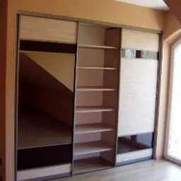 Szafa przesuwna z lustrem i półkami w jasnej kolorystyce, dopasowana do skosu dachu, widoczna na tle okna.