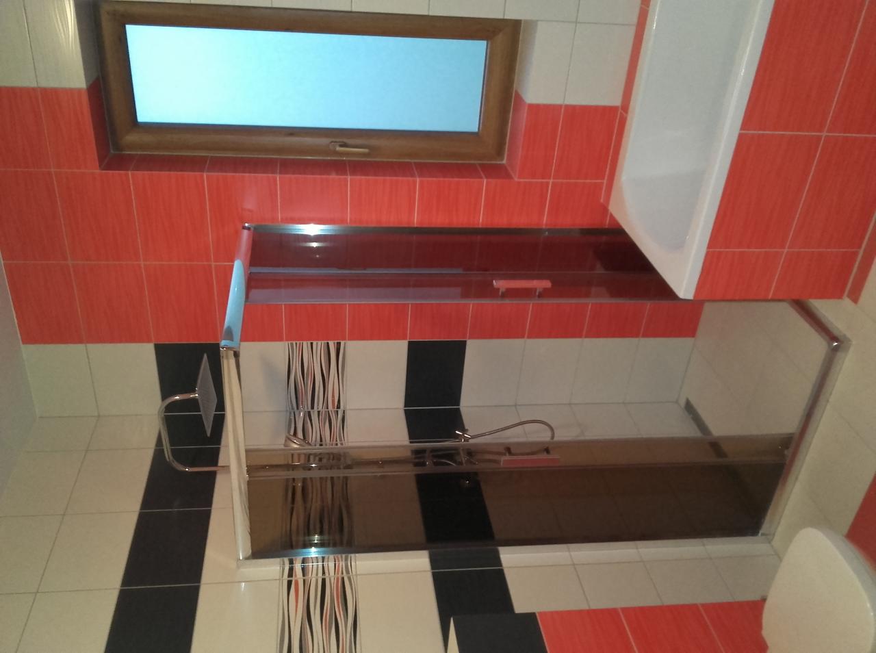 Wykończona łazienka z kabiną prysznicową, białą wanną i oknem. Czerwono-biało-czarne płytki na ścianach. Chromowana armatura. Widok na wnętrze kabiny.