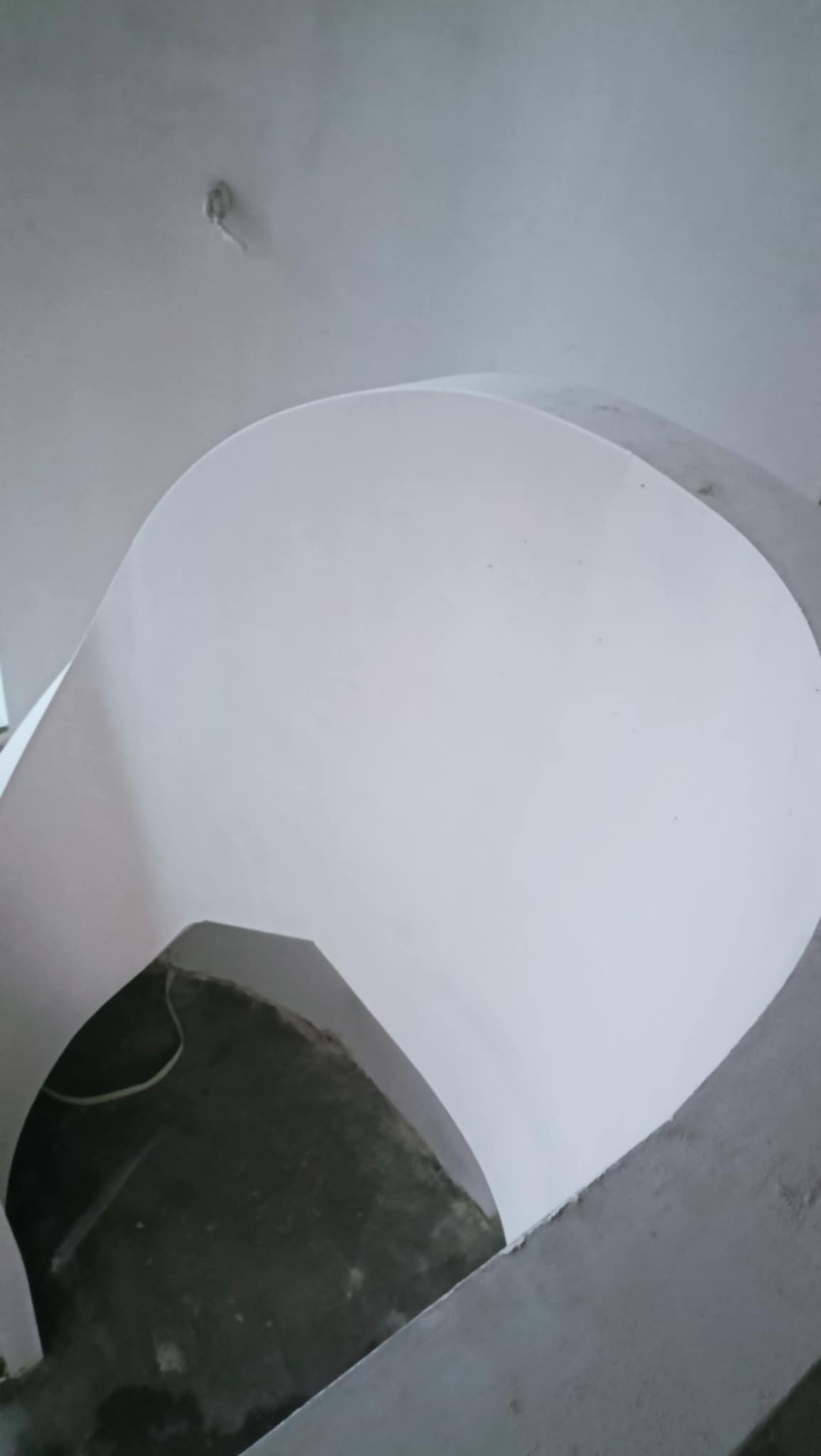 Świeżo położona, jasna, jednolita powłoka na łuku sufitowym, widoczny przewód elektryczny w tle.