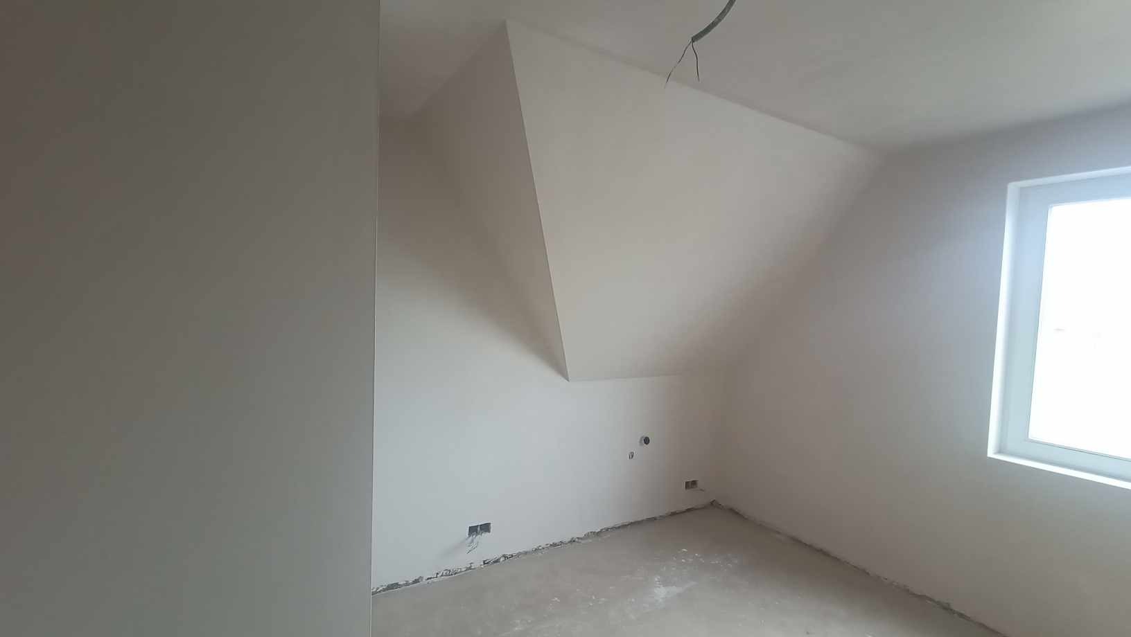 Wnętrze poddasza po nałożeniu gładzi gipsowej, widoczne wykończone ściany i sufit, przygotowane do malowania, z widocznymi puszkami elektrycznymi w ścianie.