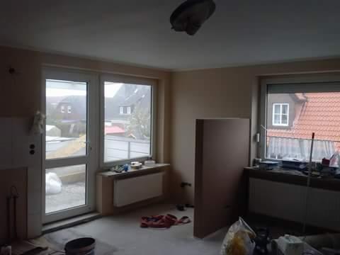 Pokój w trakcie remontu: okna, grzejniki, płyta karton-gips. Widoczne narzędzia i materiały budowlane. Stan surowy przed wykończeniem.