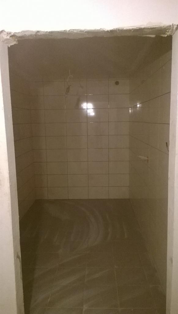 Wykończona, jasna łazienka z beżowymi płytkami w Nowej Słupi. Widoczne świeżo położone kafelki na ścianach i podłodze. Niewykończone obramowanie drzwi.