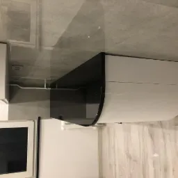 Nowoczesna łazienka w Klecza Górna z umywalką na szafce z czarnym, zaokrąglonym blatem, jasne płytki na ścianach i podłodze.