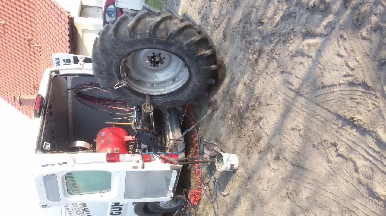 Mobilny serwis opon: demontaż opony ciągnika rolniczego przy użyciu specjalistycznego pojazdu z kompresorem i narzędziami na uboczu drogi.