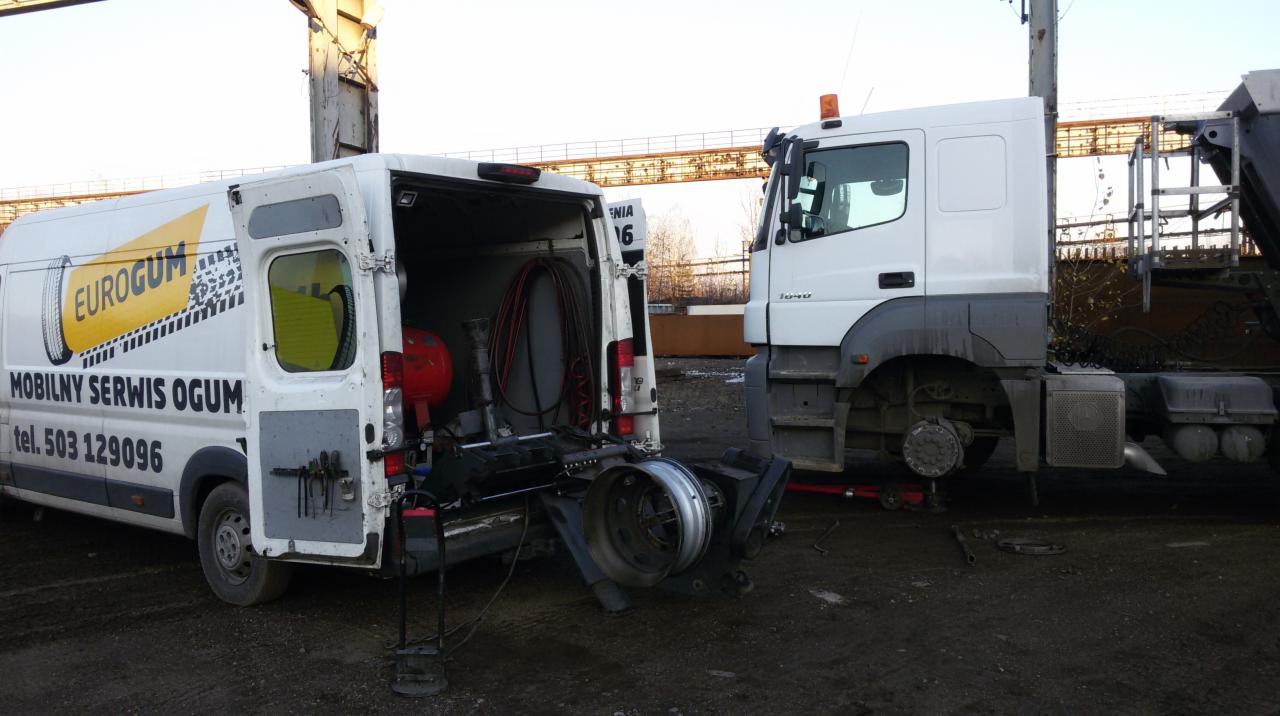 Mobilny serwis ogumienia Eurogum przy ciężarówce. W tle widoczna konstrukcja stalowa. Otwarty bus serwisowy z narzędziami do wymiany opon.