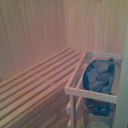 Wnętrze sauny wykończonej drewnem w Kobyłce, z widocznymi ławami i piecem z kamieniami.