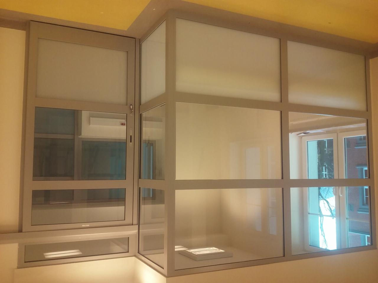 Nowoczesna zabudowa okienna z szarymi ramami i matowymi szybami, widok z dołu, fragment pomieszczenia z żółtym sufitem. Widoczne odbicia w szybach.