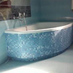 Wykończona łazienka w Lublińcu z wanną obłożoną mozaiką w odcieniach błękitu i turkusu, na ścianie dekoracyjny panel z motywem morskim.