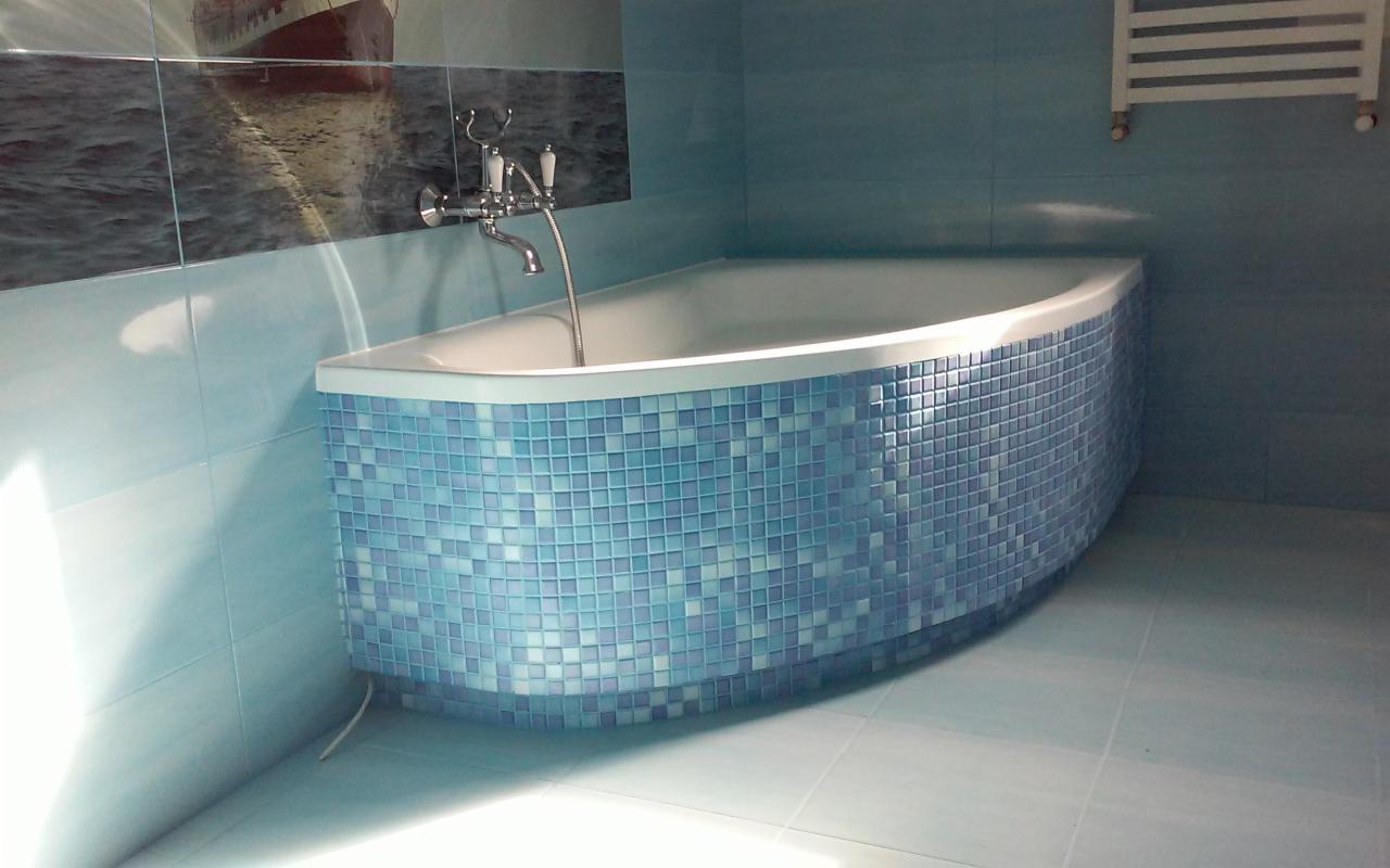 Wykończona łazienka w Lublińcu z wanną obłożoną mozaiką w odcieniach błękitu i turkusu, na ścianie dekoracyjny panel z motywem morskim.