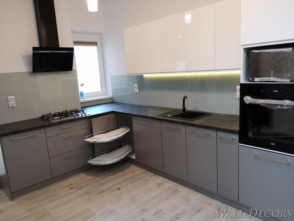 Nowoczesna kuchnia z szarymi szafkami, białymi górnymi szafkami na wysoki połysk, czarnym zlewem i płytą gazową, oraz wysuwanymi półkami narożnymi.