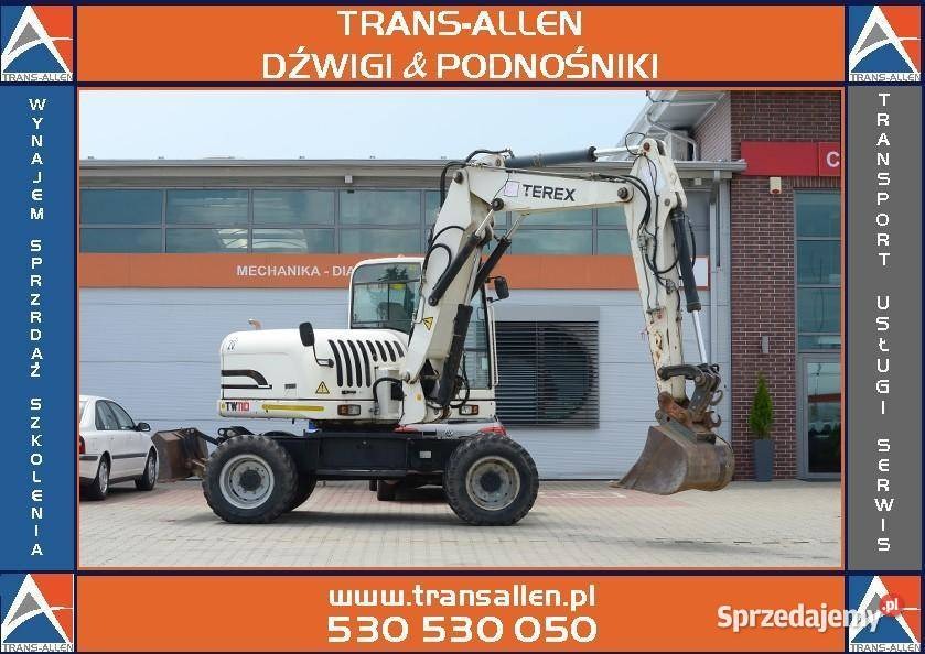 Biała koparka kołowa marki Terex na tle budynku firmy z Jasła, widoczne logo Trans-Allen, oferta wynajmu, sprzedaży i szkoleń.