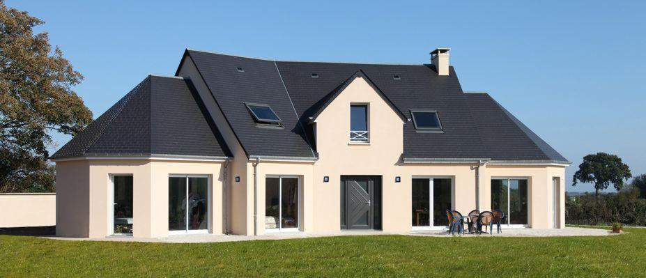 Gotowy dom szkieletowy z ciemnym dachem i jasną elewacją, widok z zewnątrz na trawnik i taras z meblami ogrodowymi. Okna dachowe i duże przesuwne okna.