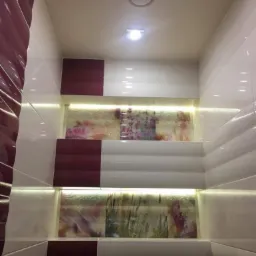 Wykończona łazienka z białymi i bordowymi płytkami, podświetlane wnęki z motywami kwiatowymi, widok od dołu.