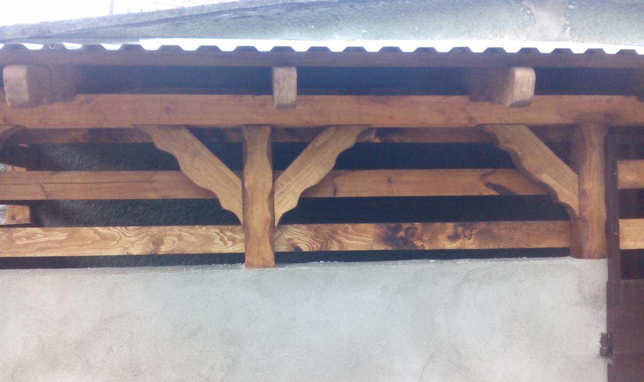 Drewniana konstrukcja z belek i wsporników, prawdopodobnie zadaszenie lub element dekoracyjny. Widoczne detale obróbki drewna i wykończenia.