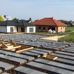 Budowa domu: widok z góry na strop Teriva z ułożonymi pustakami i zbrojeniem, w tle zabudowa jednorodzinna i zielone tereny.