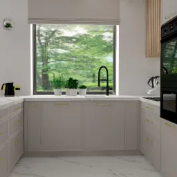 Nowoczesna kuchnia w odcieniach szarości z marmurowym blatem, złotymi uchwytami i dużym oknem z widokiem na zieleń, wyposażona w czarny czajnik i piekarnik.