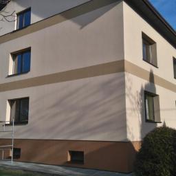 Firma Budowlana BRI Piotr Danek - Dwukondygnacyjny dom z oknami i elewacją w odcieniach beżu i brązu, z widocznymi rusztowaniami przy wejściu i anteną satelitarną na bocznej ścianie.