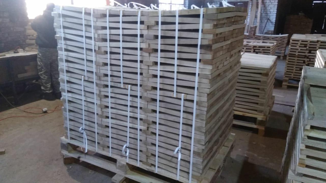 Stosy świeżo przetartego drewna ułożone na paletach, zabezpieczone białymi taśmami w hali produkcyjnej.