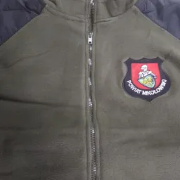 Oliwkowa bluza polarowa z czarnymi rękawami i herbem Powiatu Mikołowskiego naszytym na piersi.