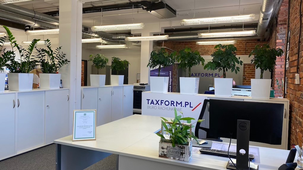 Jasne biuro z roślinami w białych donicach, logo TAXFORM.PL Biuro Rachunkowe na szafkach, biurko z komputerem i ozdobną rośliną w drewnianej skrzynce.