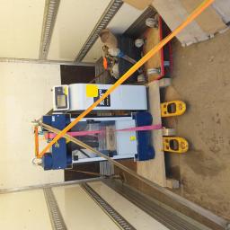 YELLOW TRANSPORT ROBERT ŻÓŁTY - Maszyna na palecie zabezpieczona pasami transportowymi wewnątrz pojazdu. Widoczne wózki transportowe i kartony. Transport specjalistyczny.