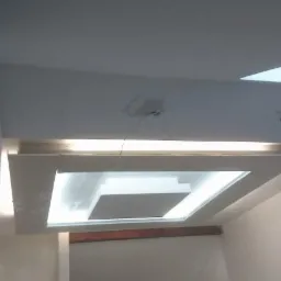 Biały sufit podwieszany z płyt kartonowo-gipsowych z wbudowanym oświetleniem LED, widok z dołu, jasne wnętrze, w trakcie montażu.