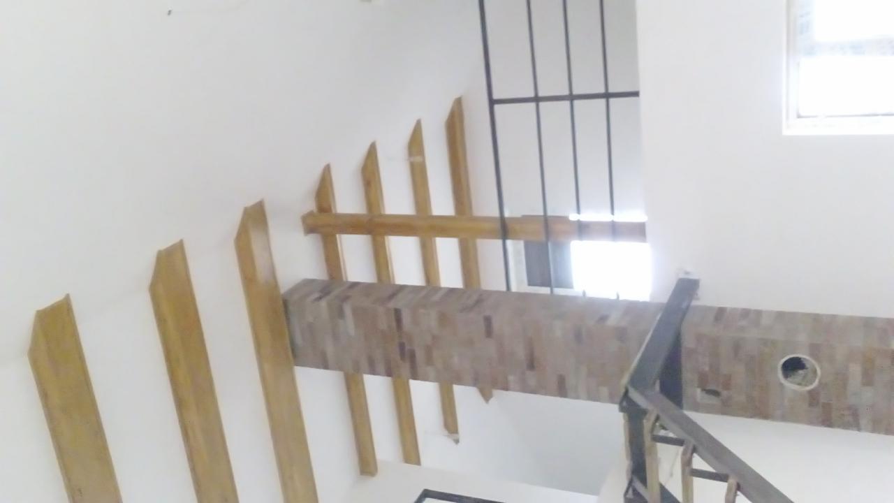 Nowoczesna balustrada schodowa z drewnianymi elementami dekoracyjnymi na białej ścianie. Widok z dołu, fragment okna i kraty w tle.