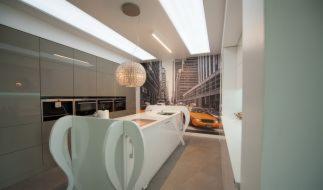 Nowoczesna kuchnia z wyspą o nietypowym kształcie, oświetleniem LED i fototapetą z motywem miejskim. Widoczny fragment żółtej taksówki.