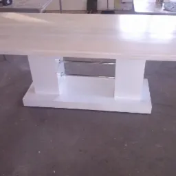 Biały stół z drewnianym blatem i metalowymi poprzeczkami, nowoczesny design, widok z przodu, szary beton na podłodze.