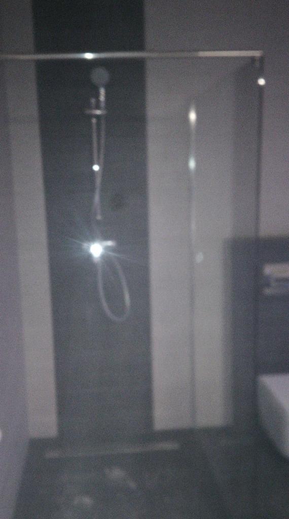 Kabina prysznicowa z szklaną ścianką i deszczownicą w nowoczesnej łazience w Chełmcu. Minimalistyczny design, ciemna armatura.