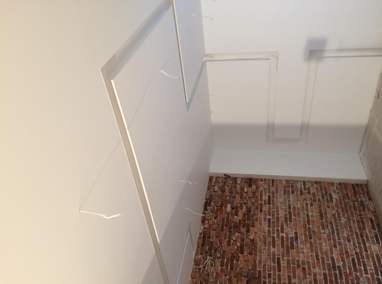 Montaż sufitu podwieszanego z płyty karton gips w Pabianicach, widoczne wystające przewody i fragment ściany z cegły.