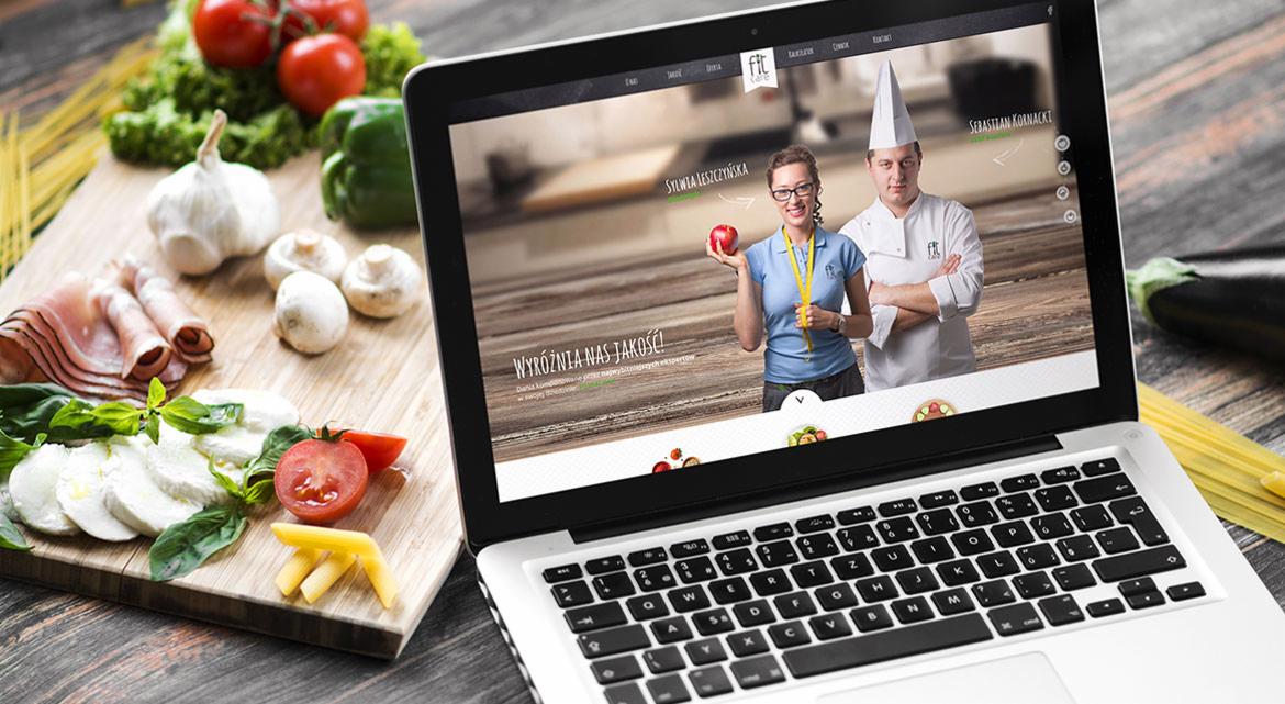 Laptop wyświetla świeży layout strony FITCARE.pl z wizerunkiem dietetyczki i kucharza, obok kompozycja kulinarna na desce, Warszawa.