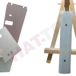 Hat-Trick Janusz Płonka - Precyzyjnie wycięte, metalowe elementy na białym tle, jeden trzymany w dłoni, drugi na drewnianym stojaku. Widoczne otwory i krawędzie. Obróbka.