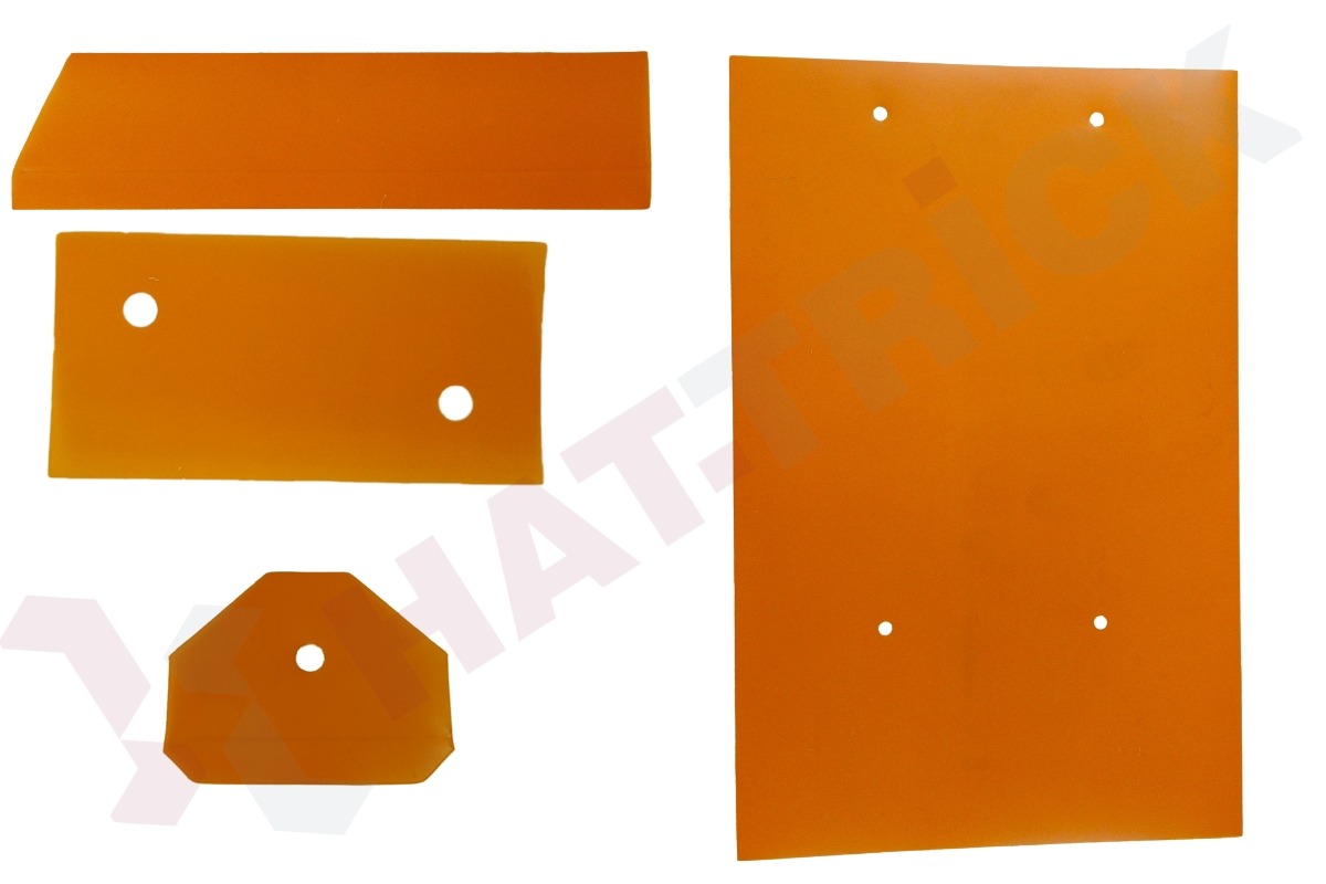 Pomarańczowe, płaskie elementy z otworami, o różnych kształtach: prostokąt, trapez, ośmiokąt, płyta. Wycięte z tworzywa sztucznego, prawdopodobnie na ploterze.