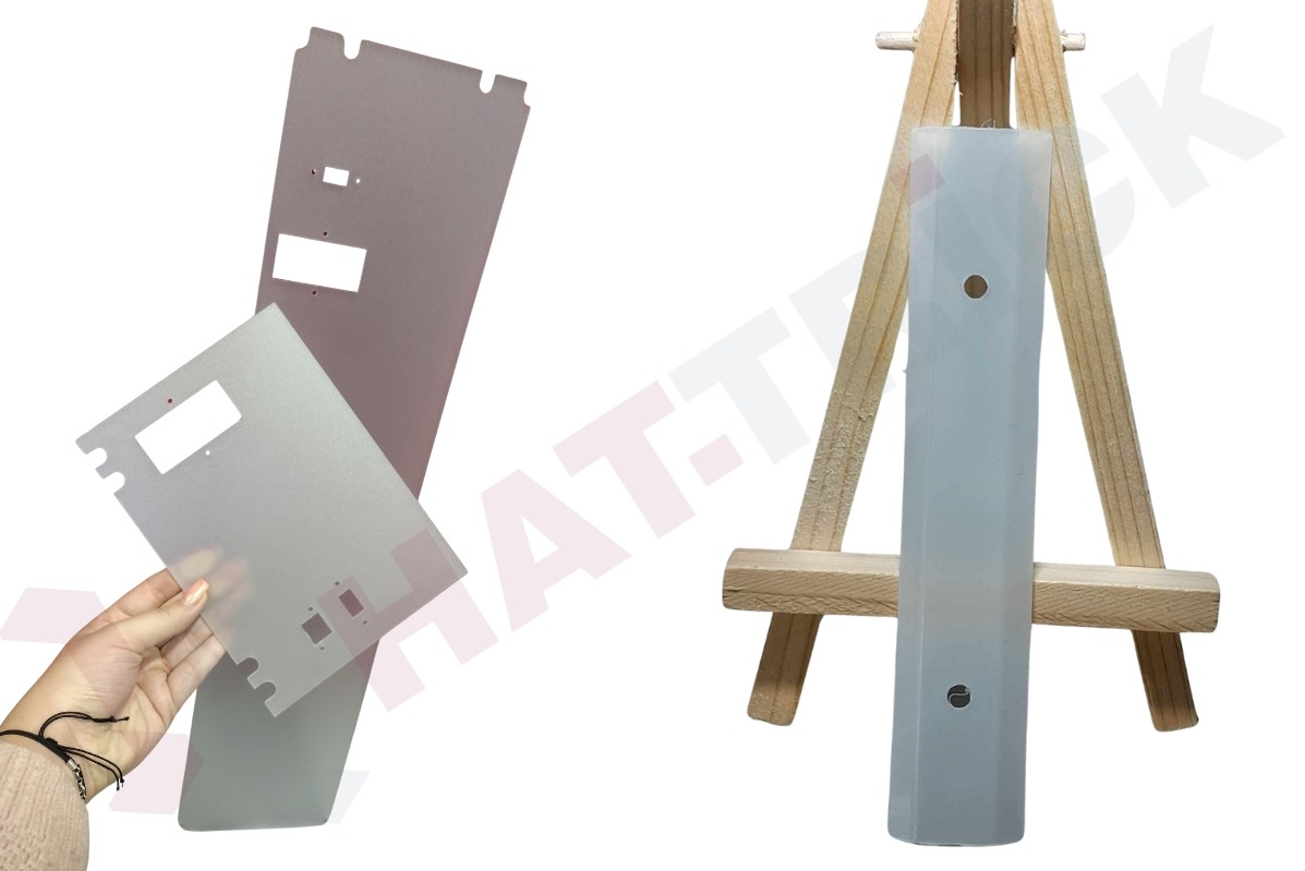 Precyzyjnie wycięte, metalowe elementy na białym tle, jeden trzymany w dłoni, drugi na drewnianym stojaku. Widoczne otwory i krawędzie. Obróbka.