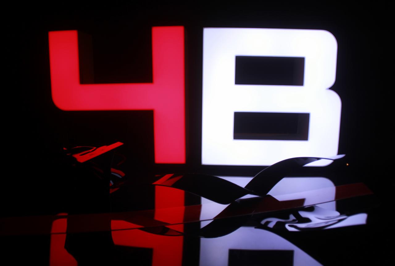 Podświetlane litery 4B, czerwona czwórka i białe B, z widocznymi elementami montażowymi i odbiciem na błyszczącej powierzchni, na czarnym tle.