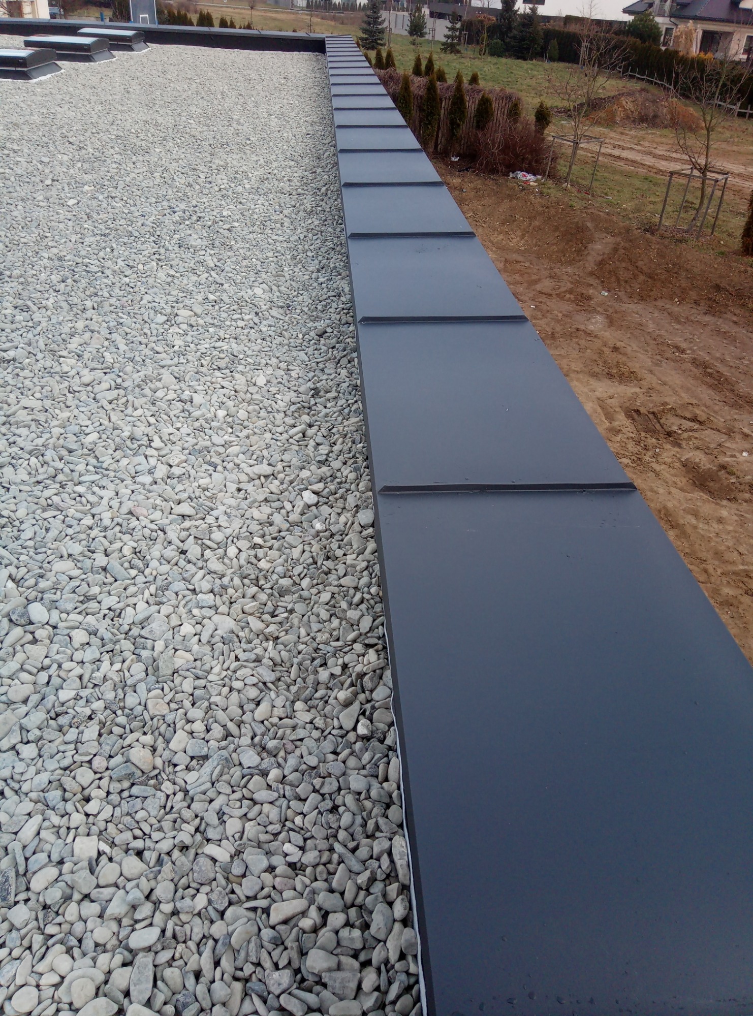 Wykończony dach pokryty drobnym żwirem w Stoczku Łukowskim, z widoczną metalową obróbką blacharską krawędzi dachu.