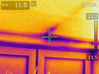 Termowizja: obszar okna z nieszczelnością, widoczny jako ciemniejszy, chłodniejszy punkt na tle cieplejszej ściany. Analiza termiczna budynku po ociepleniu.